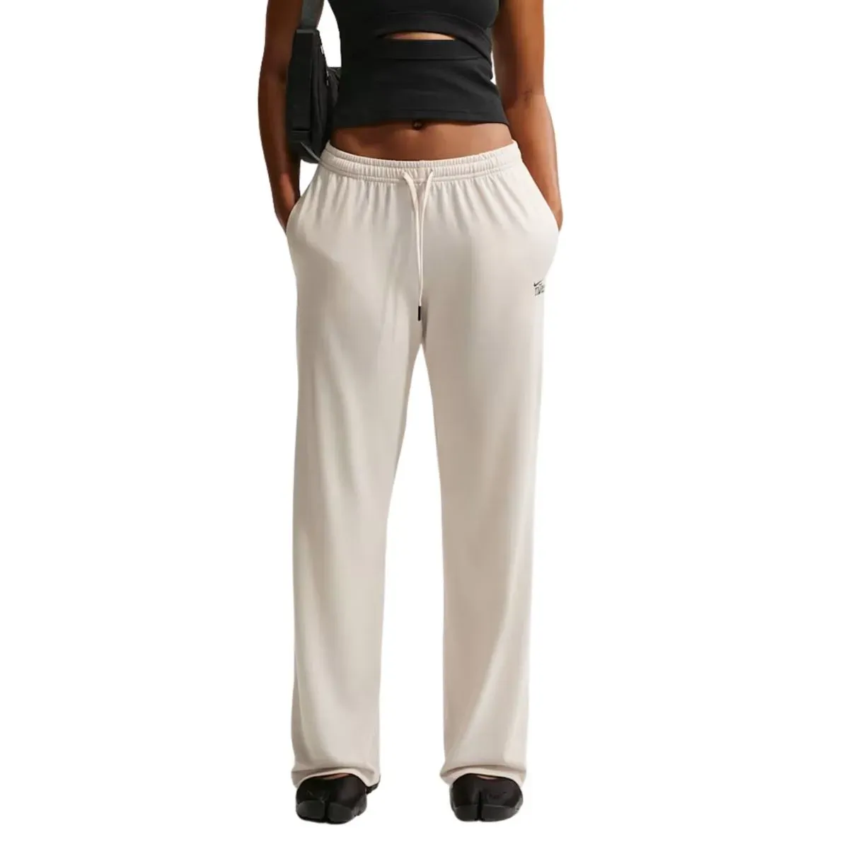 Mulher vestindo calça casual feminina Nike Chill Knit cinza, vista lateral com detalhes do tecido e logotipo Nike